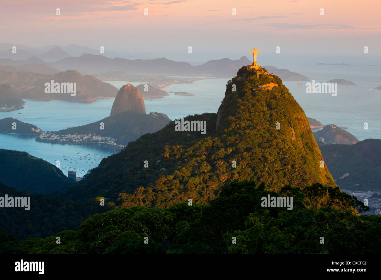Christ, the Redeemer statue sunset Rio de Janeiro, Brazil. Sugar Loaf Mountain in the background. Brazil landmarks Tijuca forest Stock Photo