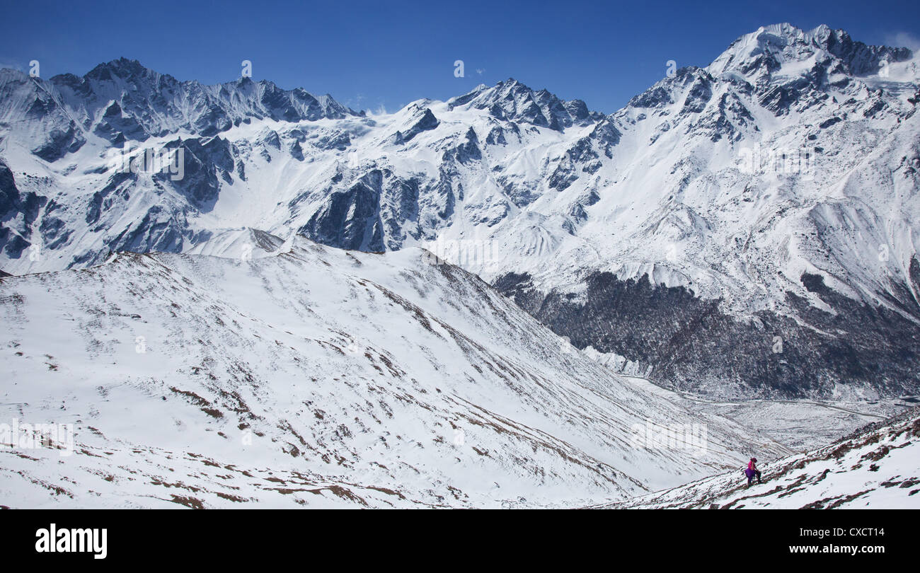 Woman trekking up the side of a snow covered mountain, Langtang Valley ...