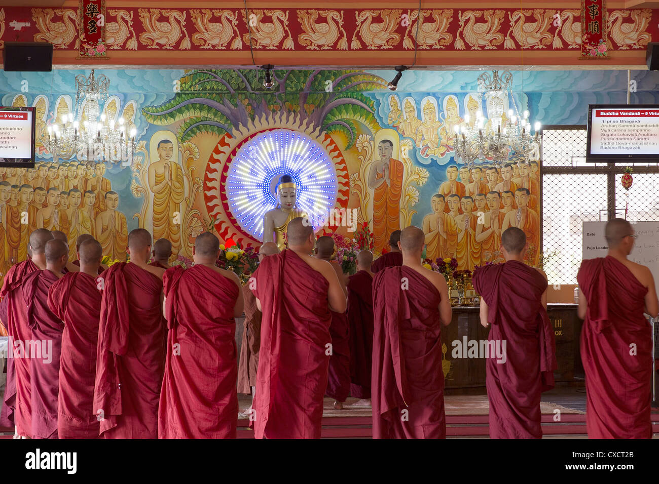 Buddhist Monks Worshipping Buddha in Temple Altar with Painted Murals of Disciples and Bodhisattvas Stock Photo