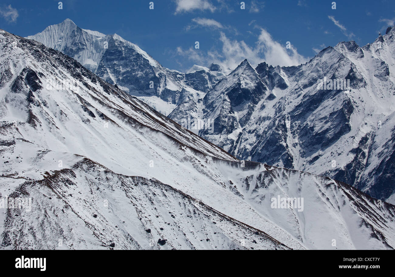 View over a mountain covered with snow to higher snowcapped mountains in the distance, Langtang Valley, Nepal Stock Photo