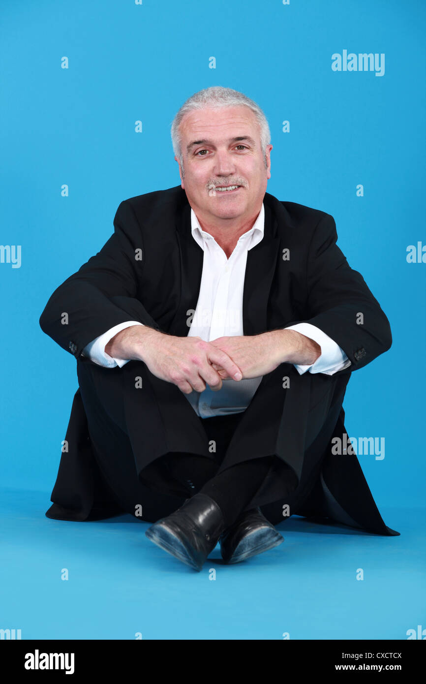 Senior businessman sitting on the floor Stock Photo - Alamy