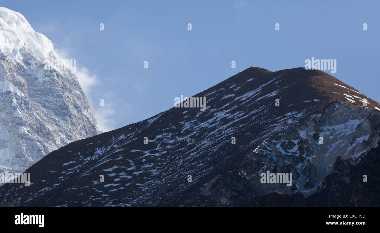 Hillside partly covered in snow with a huge snowcapped mountain in the distance,  Langtang Valley, Nepal Stock Photo