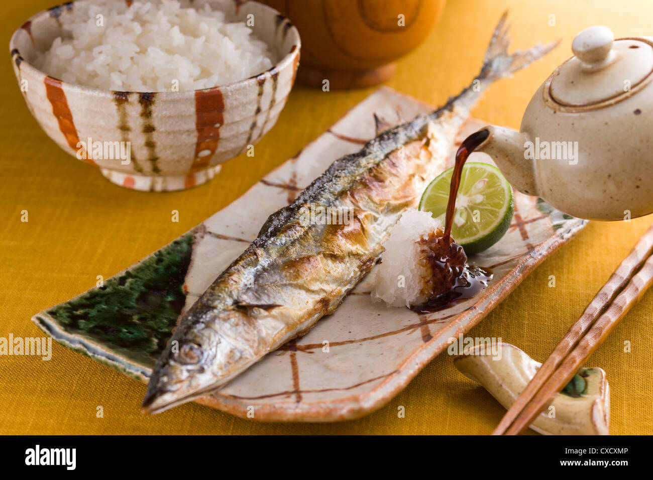 Pouring Soy Sauce on Grilled Pacific Saury and Grated Daikon Stock Photo