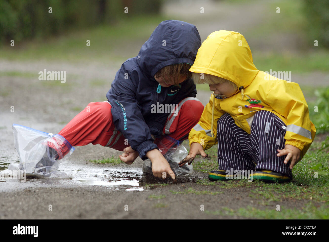 Berlin children playing in rain gear in a puddle Stock Photo