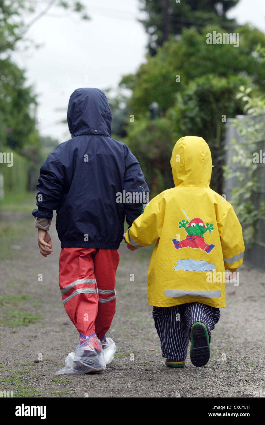 Berlin children in raincoats go hand in hand Stock Photo