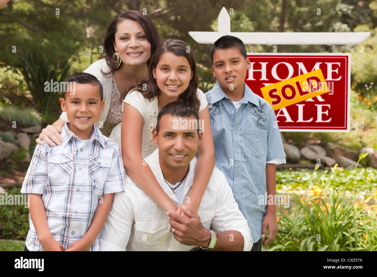 Happy Hispanic Family in Front of Sold Home for Sale Real Estate Sign ...