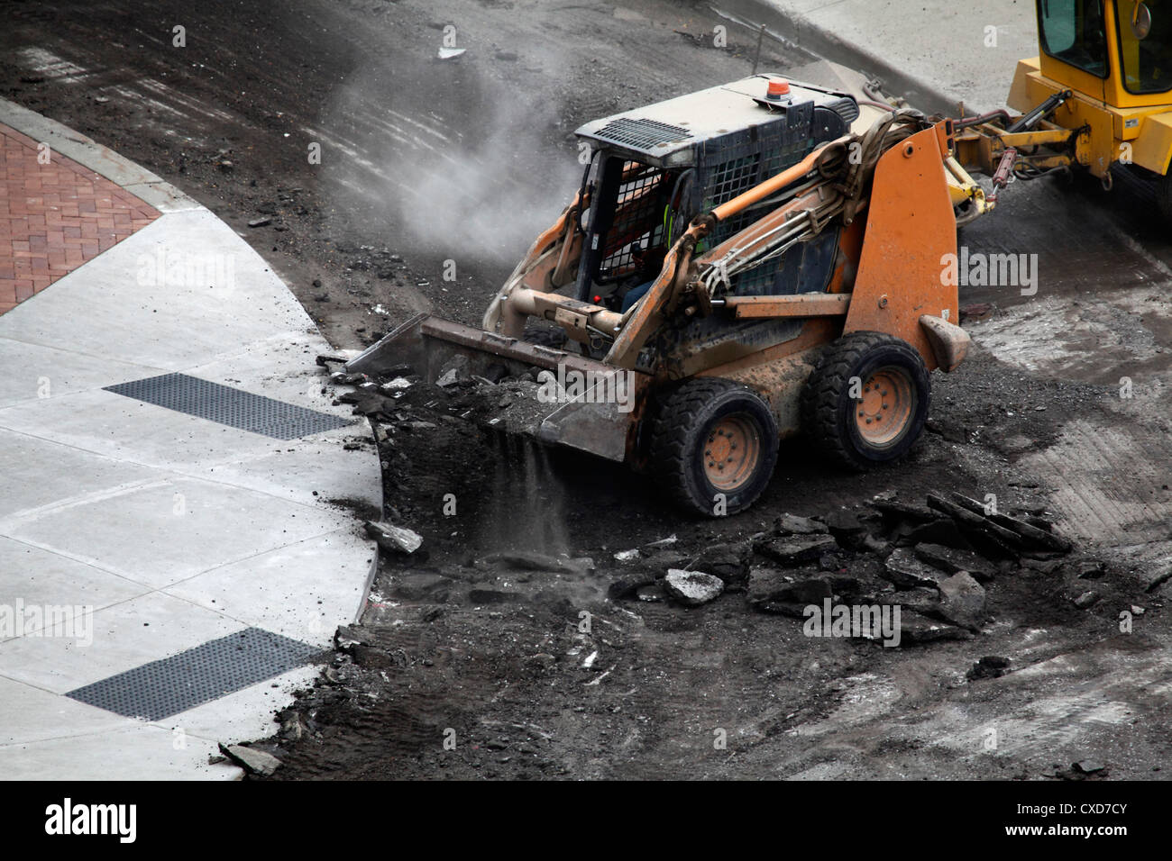 Skid loader picking up asphalt debris. Stock Photo