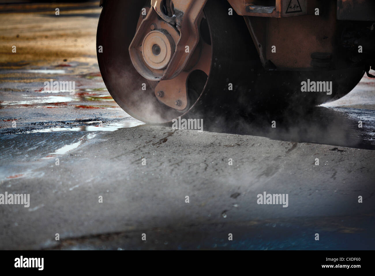 Steamroller roller on asphalt, with steam. Stock Photo