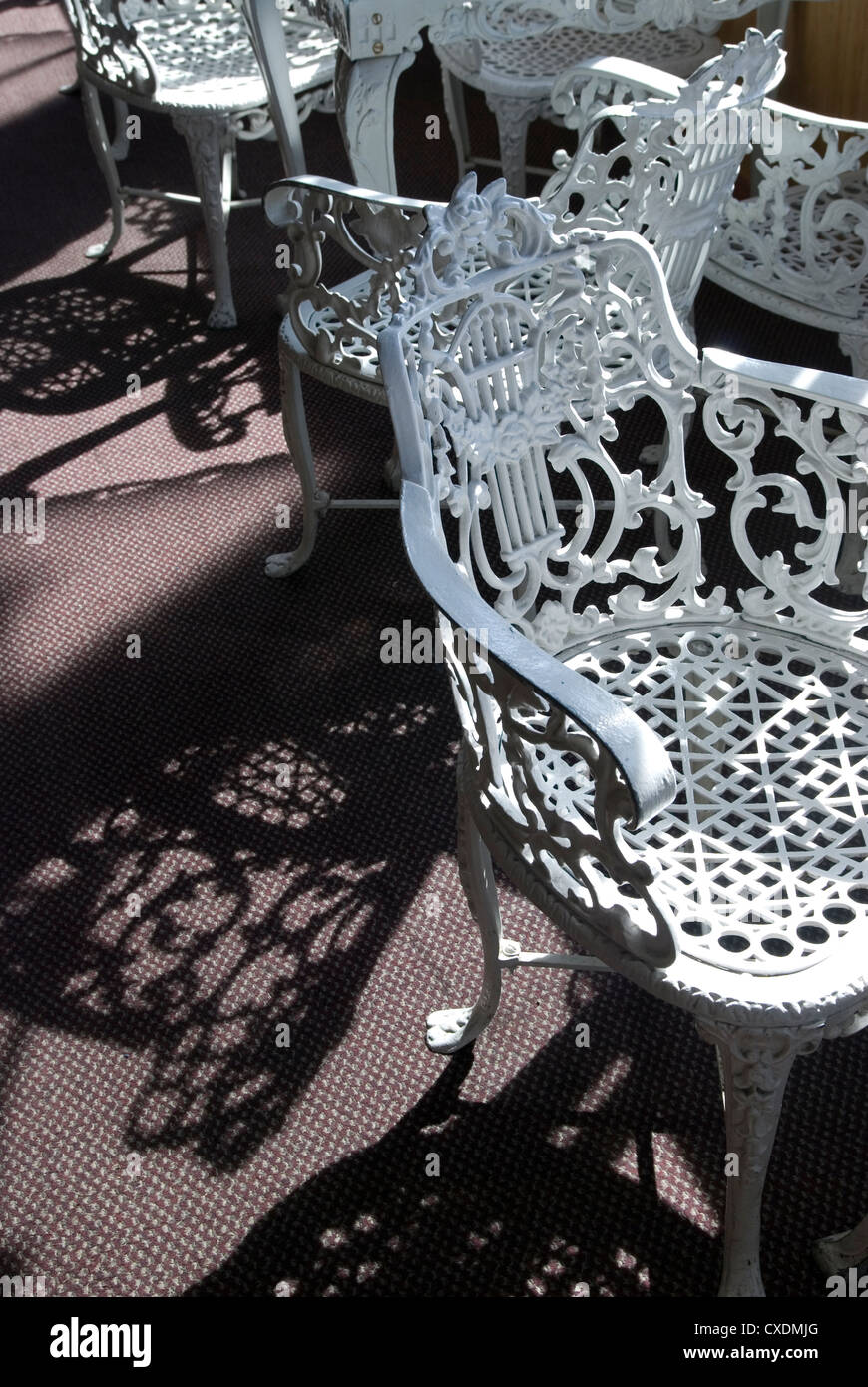 Antique white-painted wrought iron chairs sit in the sunlight on paddle wheel riverboat. Stock Photo