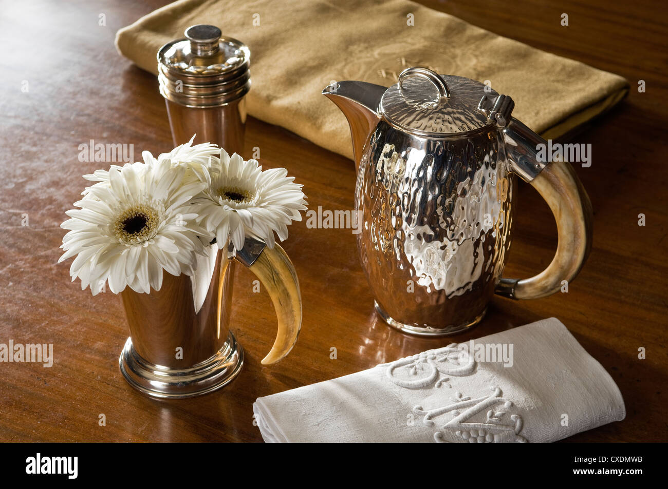 Tusk and silver plated beaker and coffee pot with linen napkin and vegetable-dyed tablecloth Stock Photo