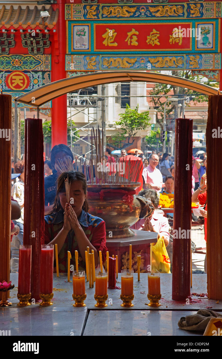 lighting candles and incense for good luck during Chinese New Year at Wat Mangkon Kamalawat in