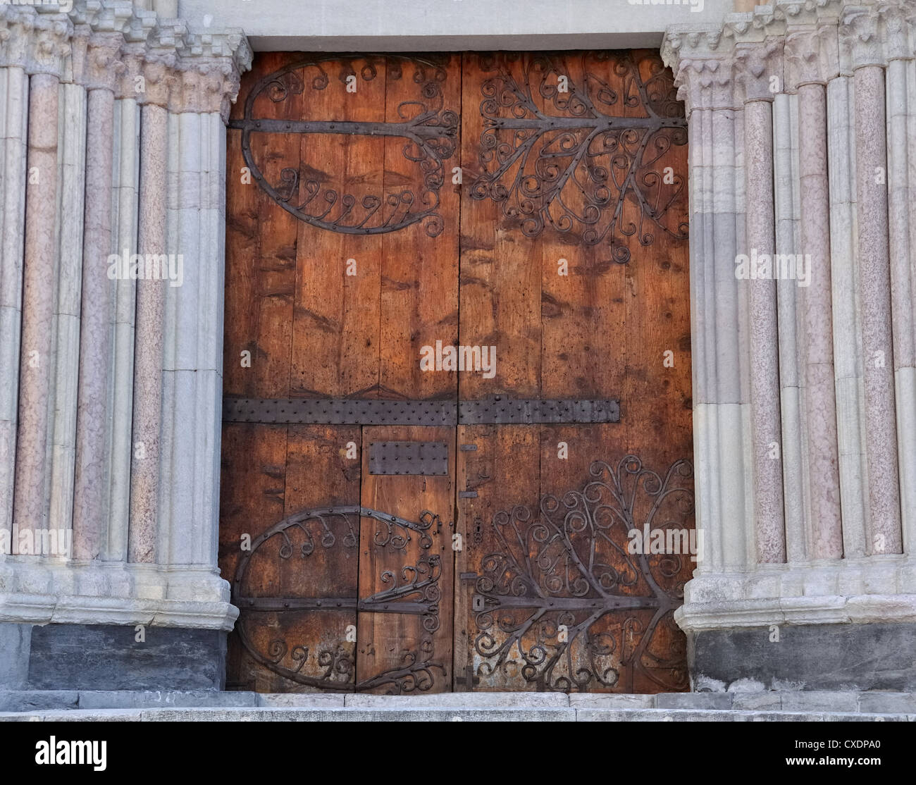 large wooden door and fitting of a cathedral flanked by marble columns Stock Photo
