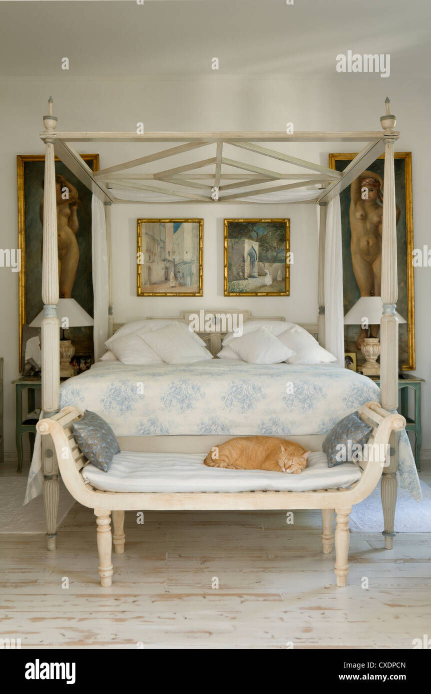 A quilt with a pale blue floral design highlights the blue and white paintwork of an antique French four-poster bed Stock Photo