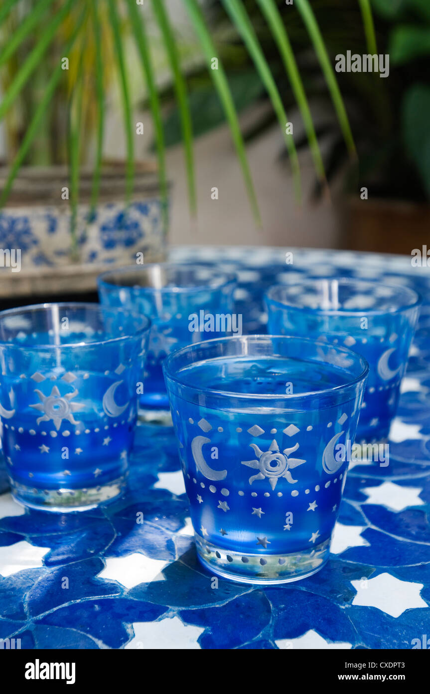Hand painted blue coloured drinking glasses on mosaic tiled tabletop Stock Photo