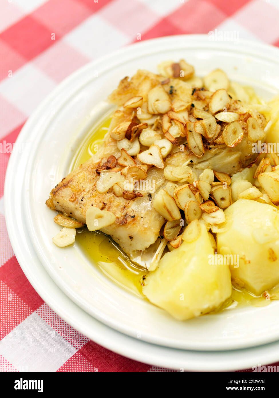 Salted Codfish with garlic and potatoes, a popular and traditional Portugese entree is paired with a nice full bodied wine. Stock Photo