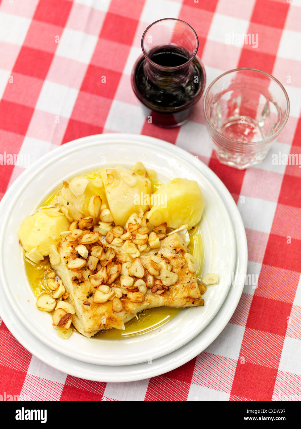 Salted Codfish with garlic and potatoes, a popular and traditional Portugese entree is paired with a nice full bodied wine. Stock Photo