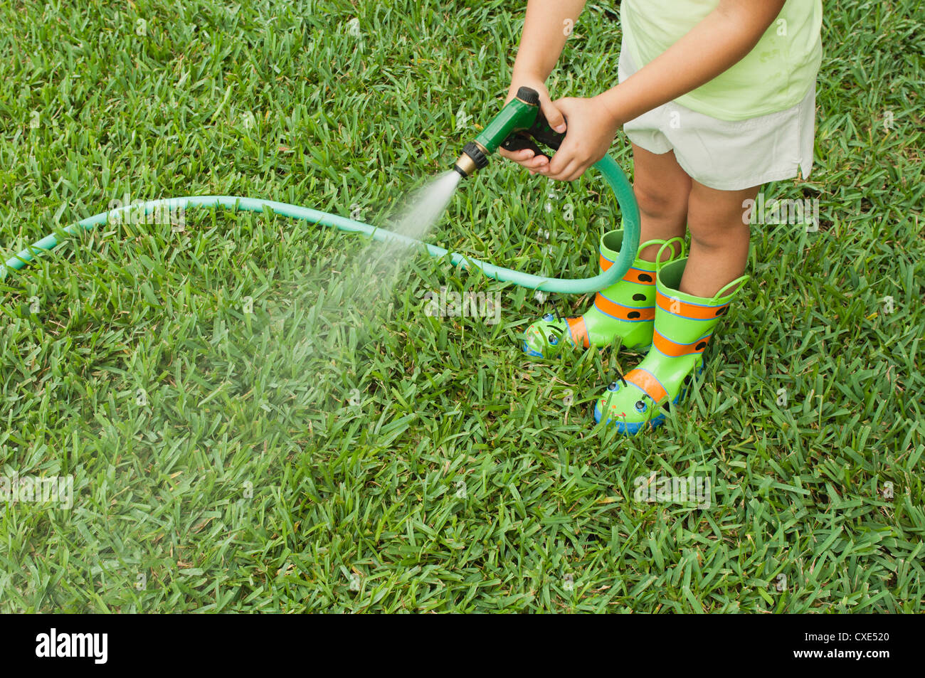 Girl watering lawn with garden hose, cropped Stock Photo Alamy