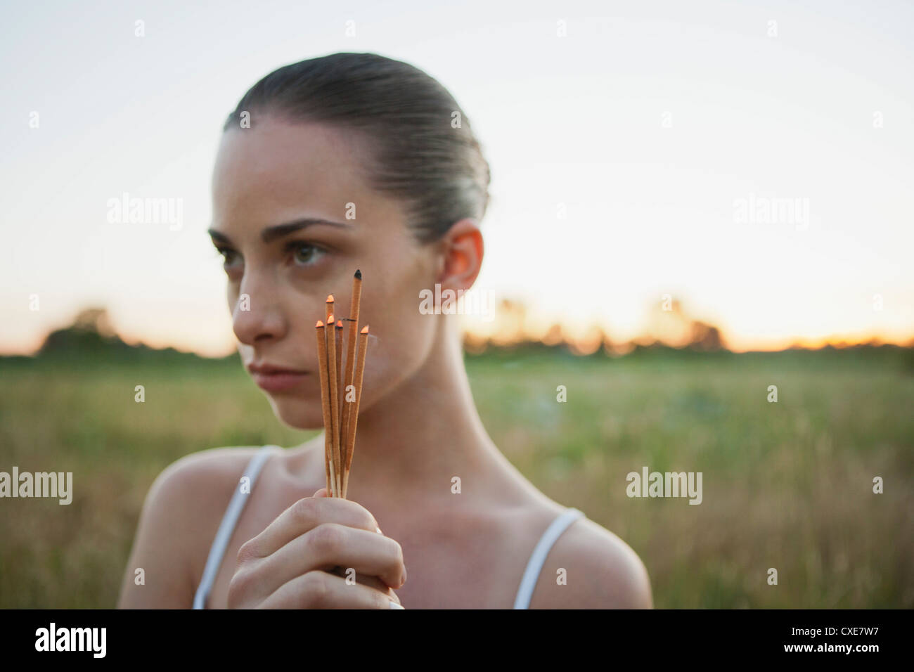 Young woman holding incense sticks outdoors Stock Photo - Alamy