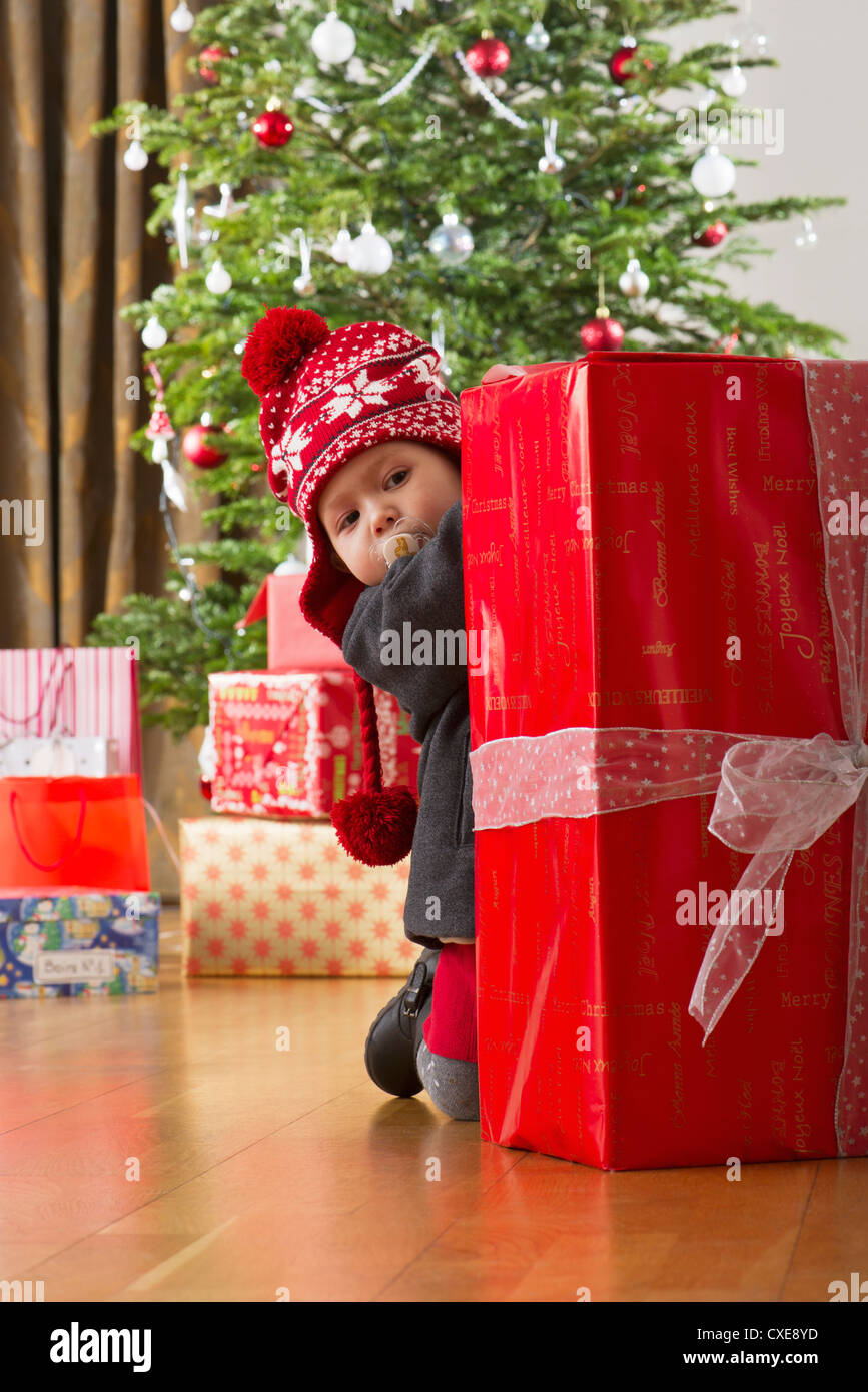 Baby girl peeking at large Christmas present Stock Photo Alamy