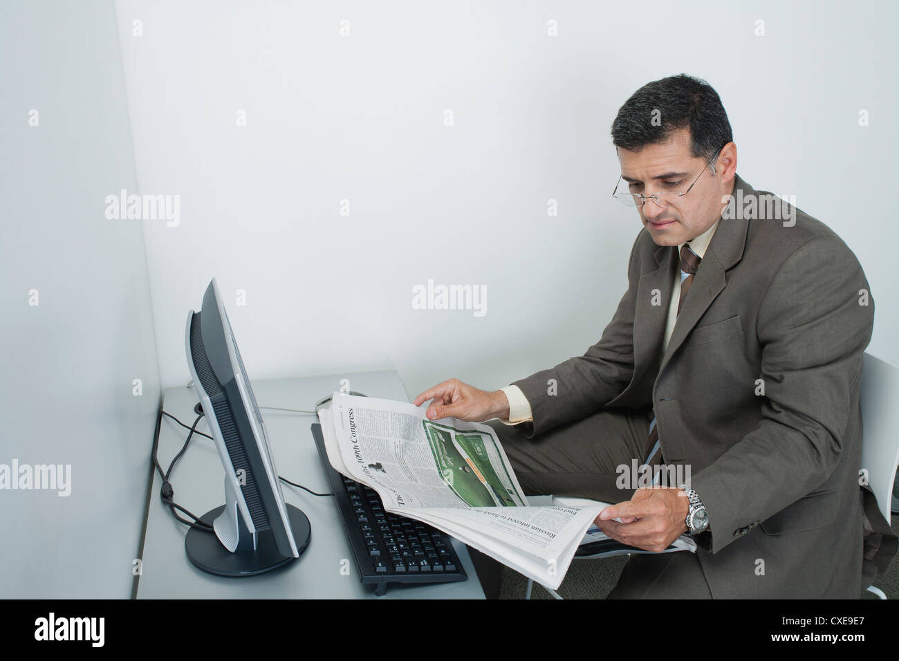 Businessman reading newspaper in office Stock Photo