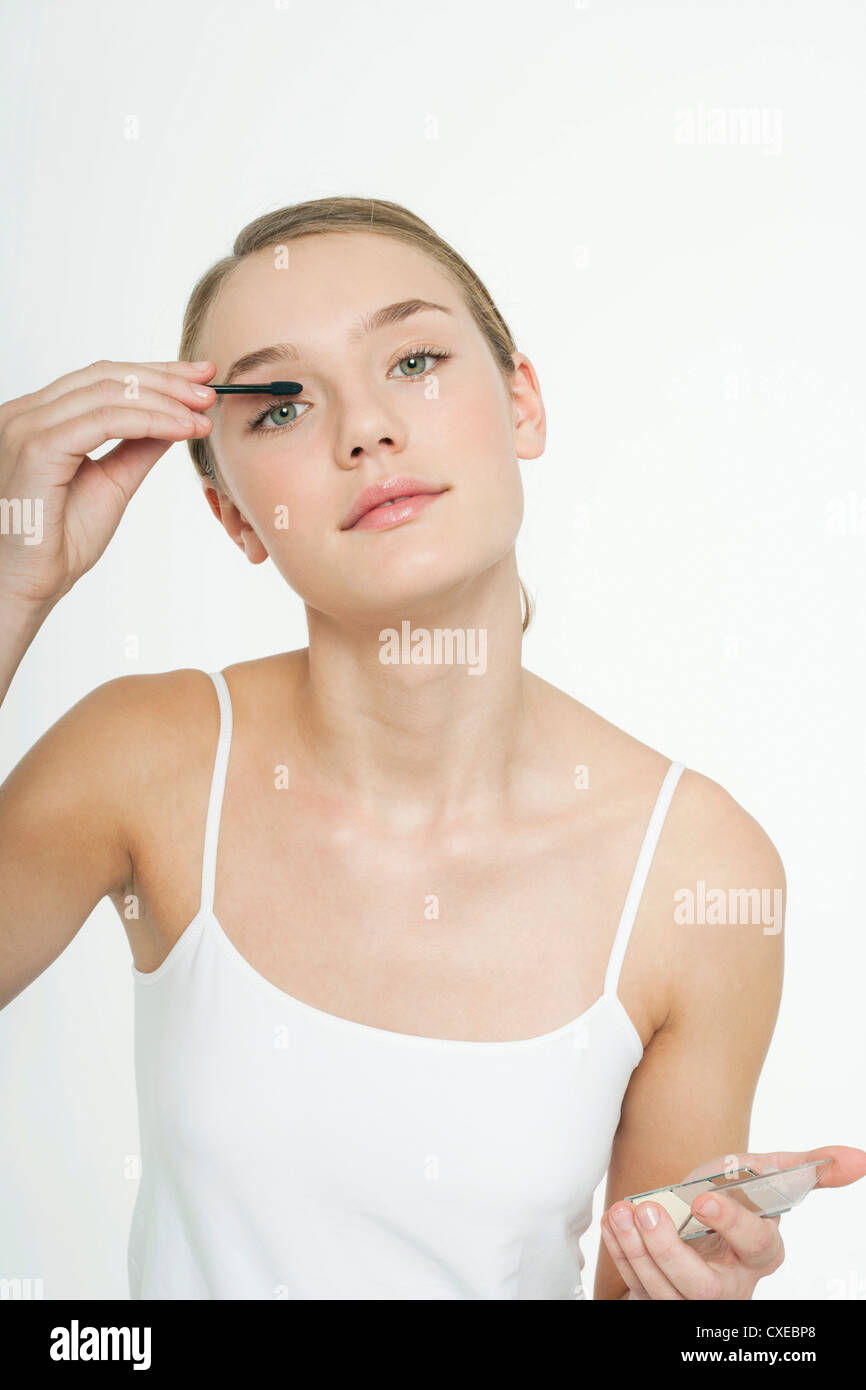 Preteen girl putting on eye shadow Stock Photo
