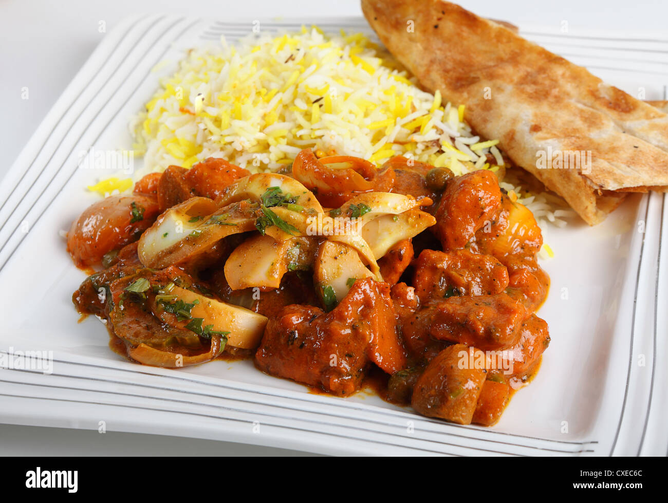 Chicken jalfrezi curry on a plate with pilau rice and a piece of naan bread. Stock Photo