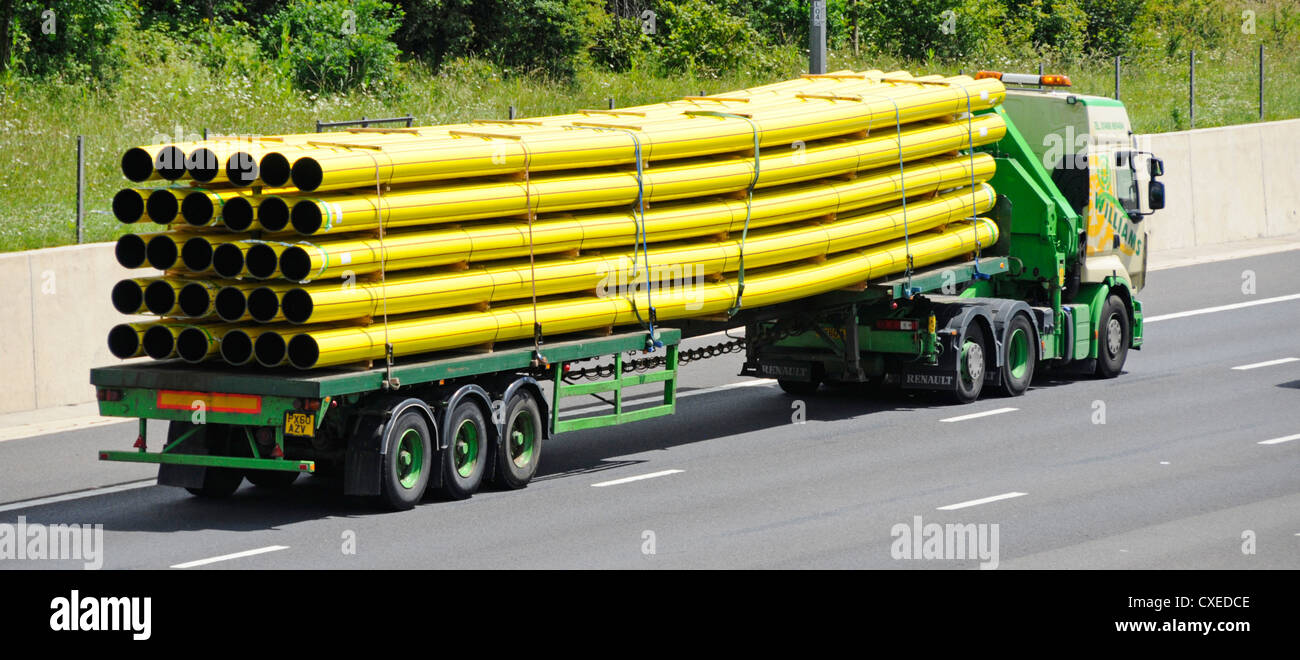 Side & back view lorry truck articulated trailer load of yellow flexible sagging plastic gas pipes commercial vehicle driving on English UK motorway Stock Photo