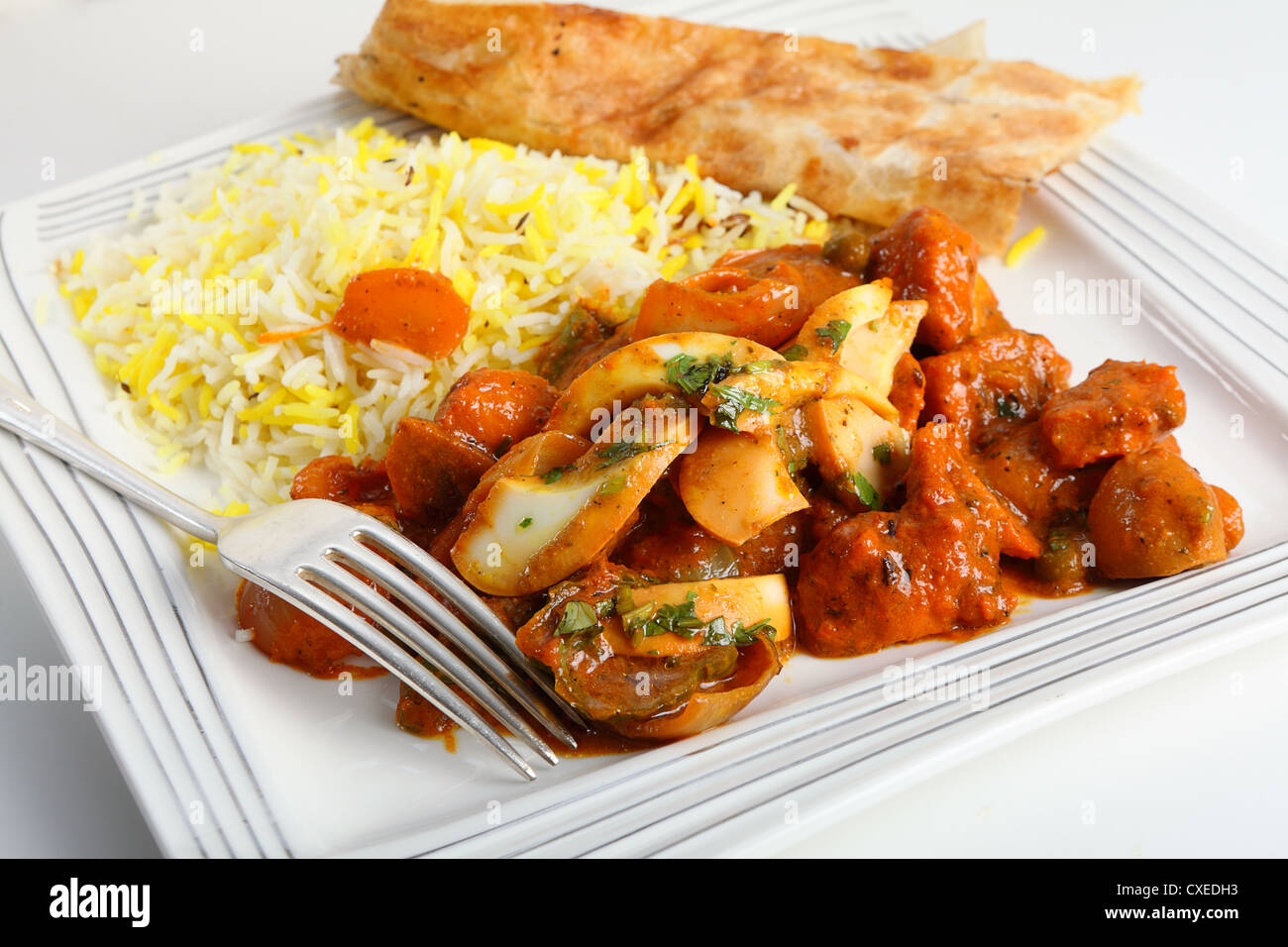 Chicken jalfrezi curry on a plate with pilau rice and a piece of naan bread. Stock Photo