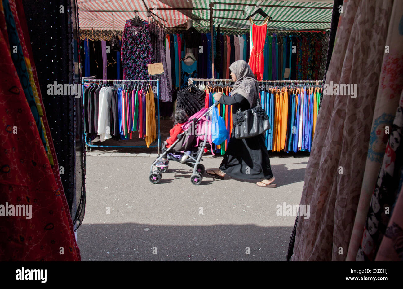 MUSLIM WOMAN WITH CHILD IN PRAM SHOPPING IN WATNEY STREET MARKET IN