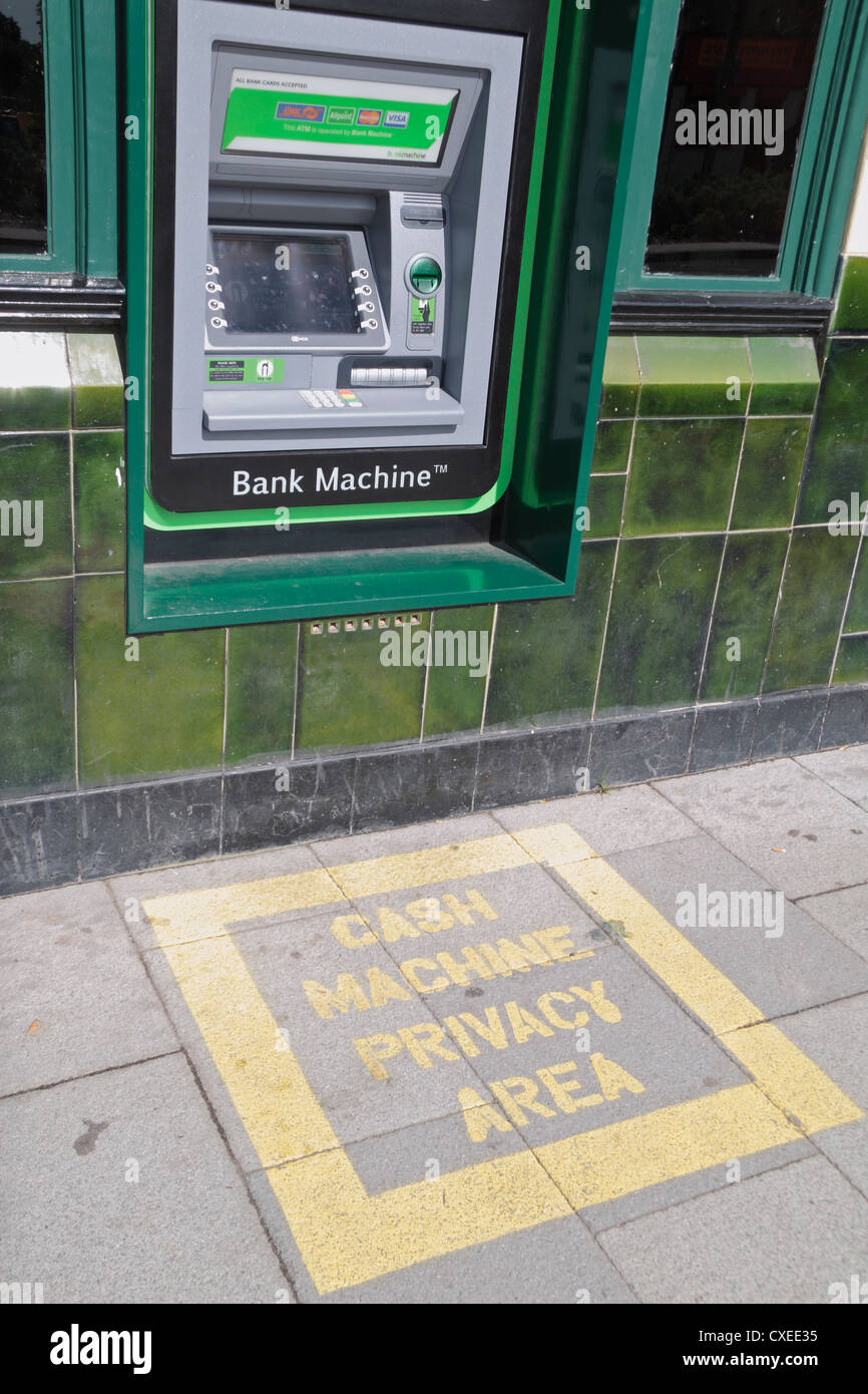 A Bank Machine ATM machine with a painted cash machine privacy area outside a public house in Stratford, London, UK. Stock Photo