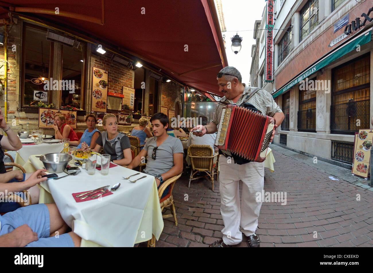 Brussels, Belgium. Busker with an accordion trying to get money from restaurant customers in the street Stock Photo
