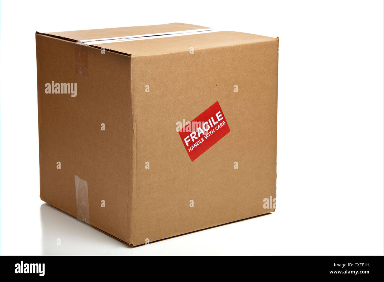 A blank, brown, corrugated cardboard box or shipping box with a 'Fragile - Handle with Care' sticker on a white background Stock Photo