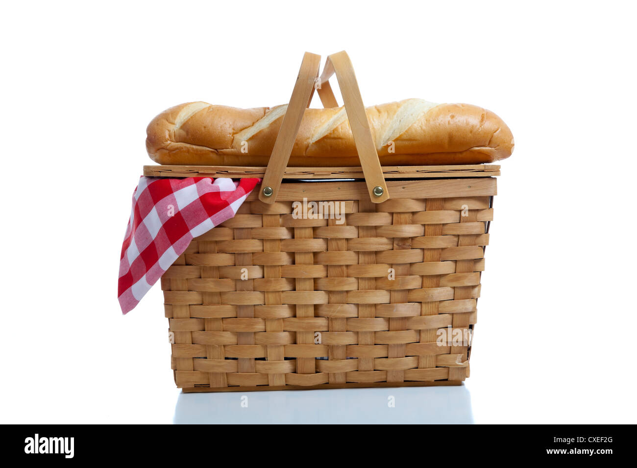 A wicker picnic basket with a red gingham cloth and bread on a white ...