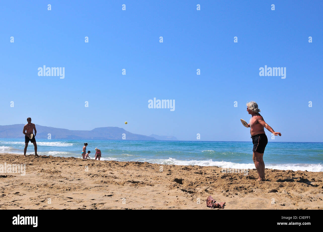 Two men playing  bat and ball.on Paralia  Kouma beach -West of Rethymnon  Crete Stock Photo