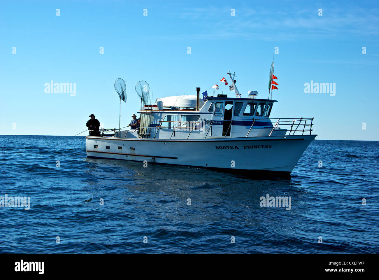 Anglers drift jigging from fishing group party boat rolling in open Pacific Ocean swells Ucluelet BC Stock Photo