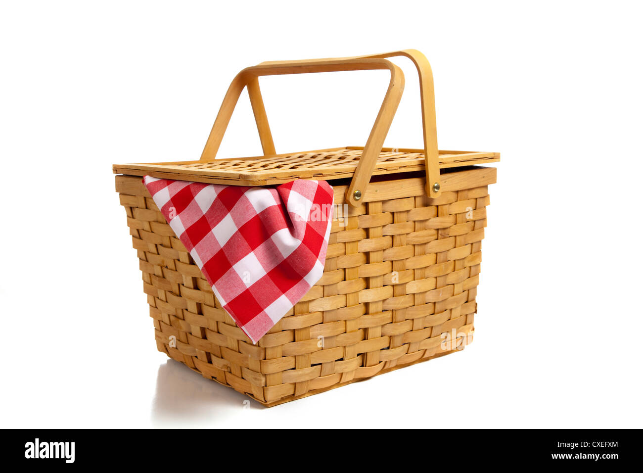 A wicker picnic basket with a red gingham cloth on a white background Stock Photo