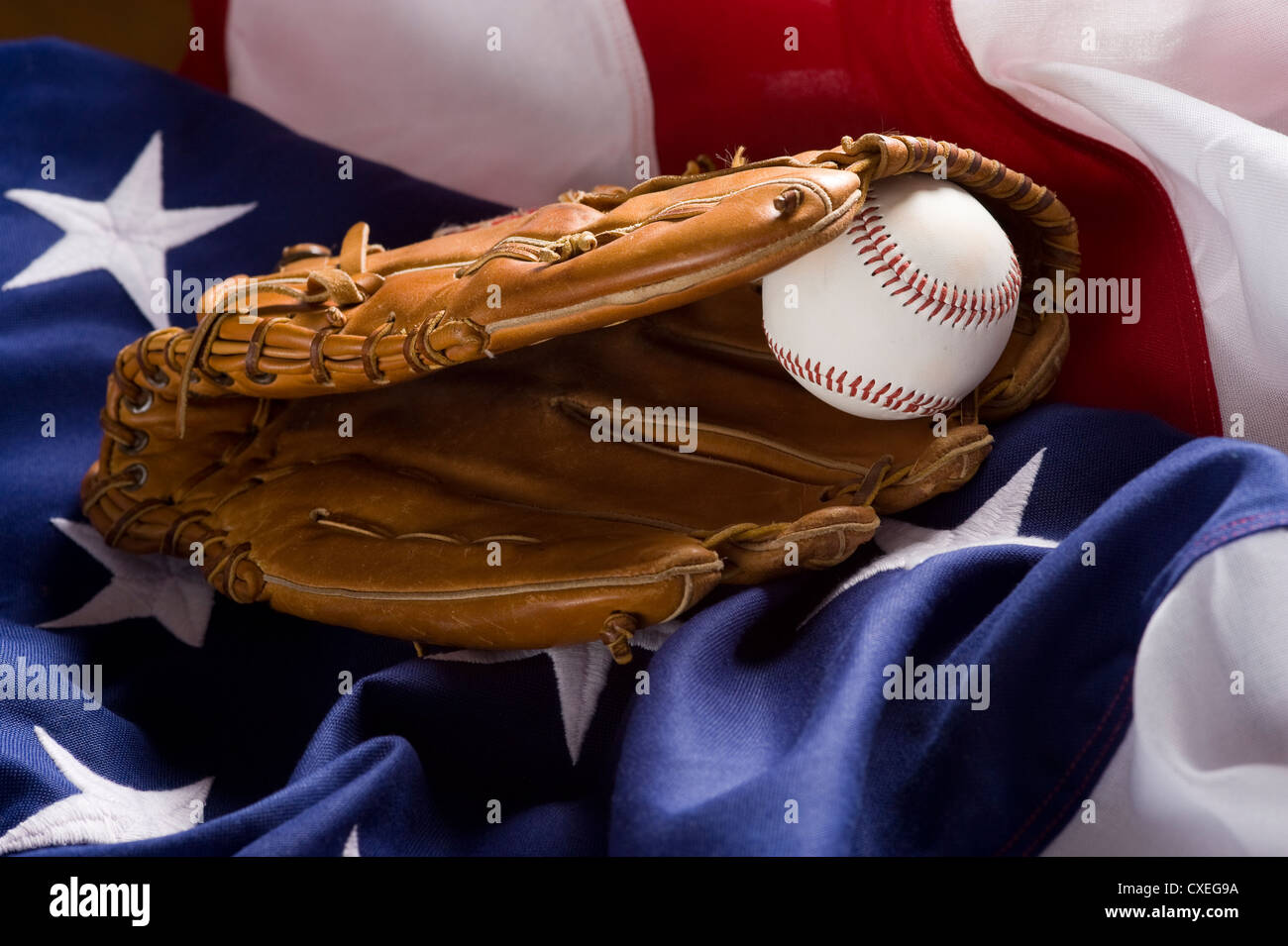 A baseball glove with a ball lying on top of an American Flag. Stock Photo