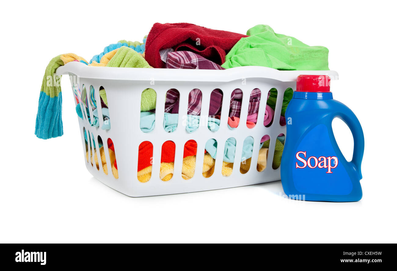 A white plastic laundry basket full of dirty clothes with laundry soap on a white background Stock Photo