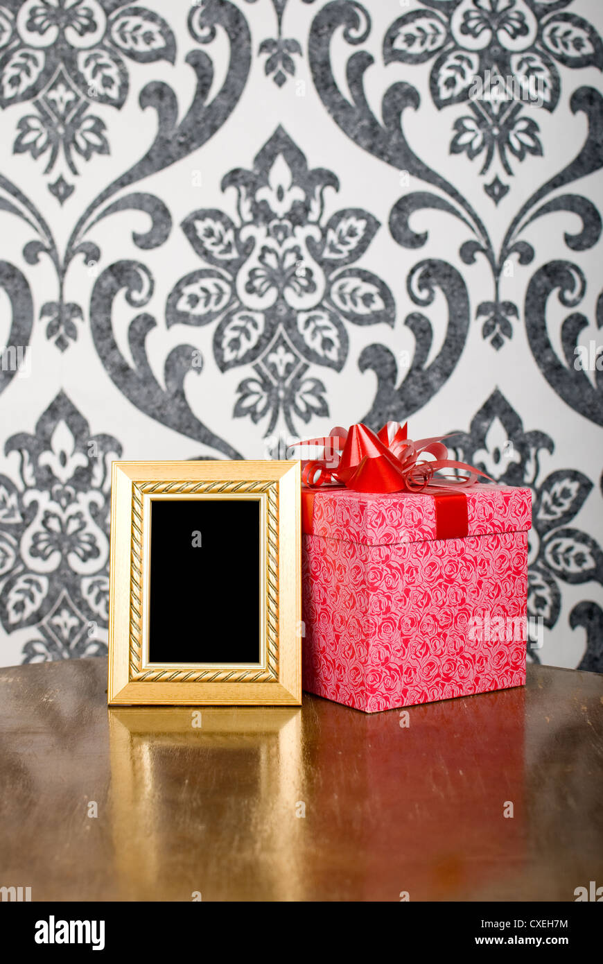 Golden photo frame and present box on table Stock Photo