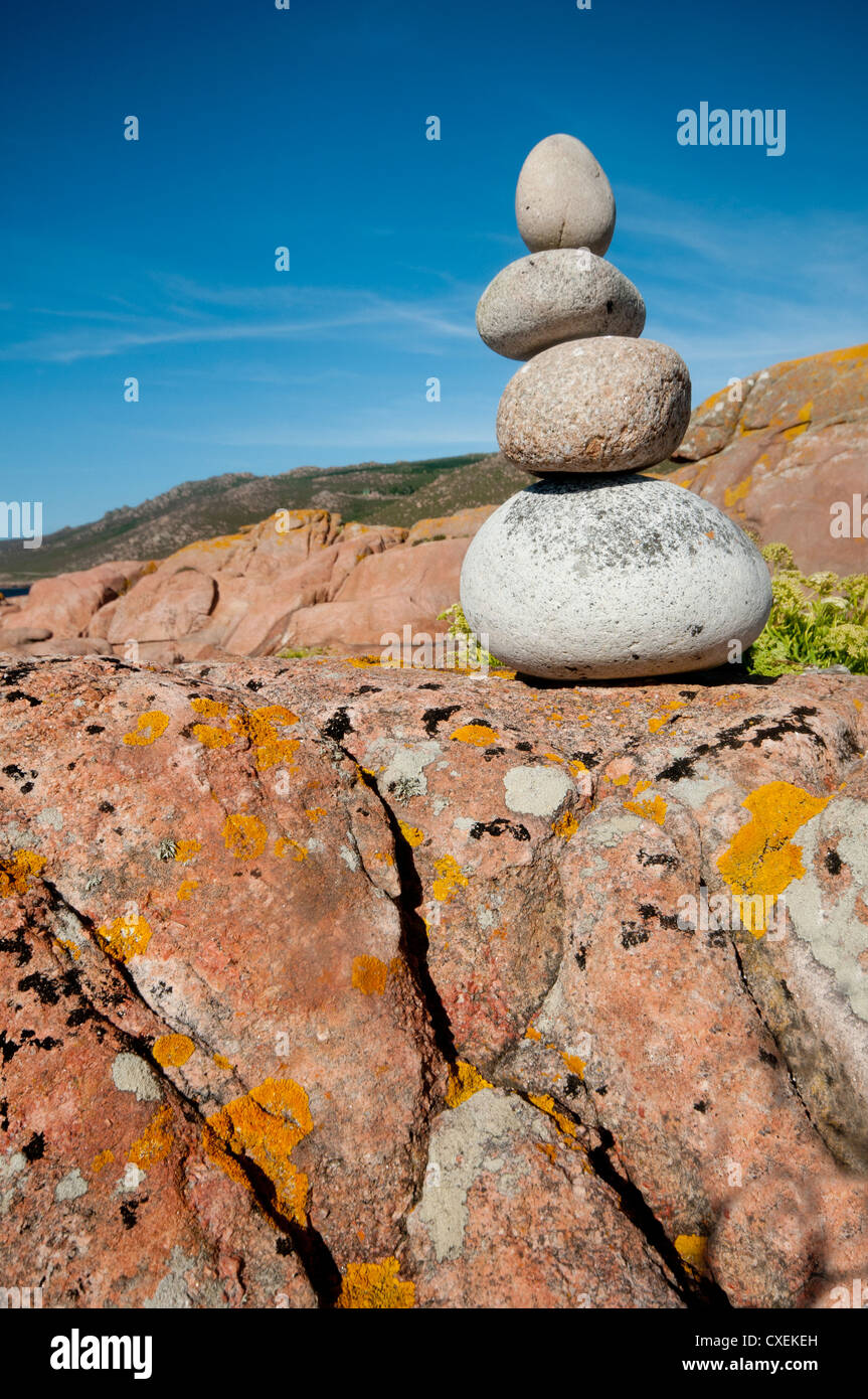 Harmonious pile of four rounded granite stones set on a lichen covered granite rock by the Galician seaside. Spain. Stock Photo