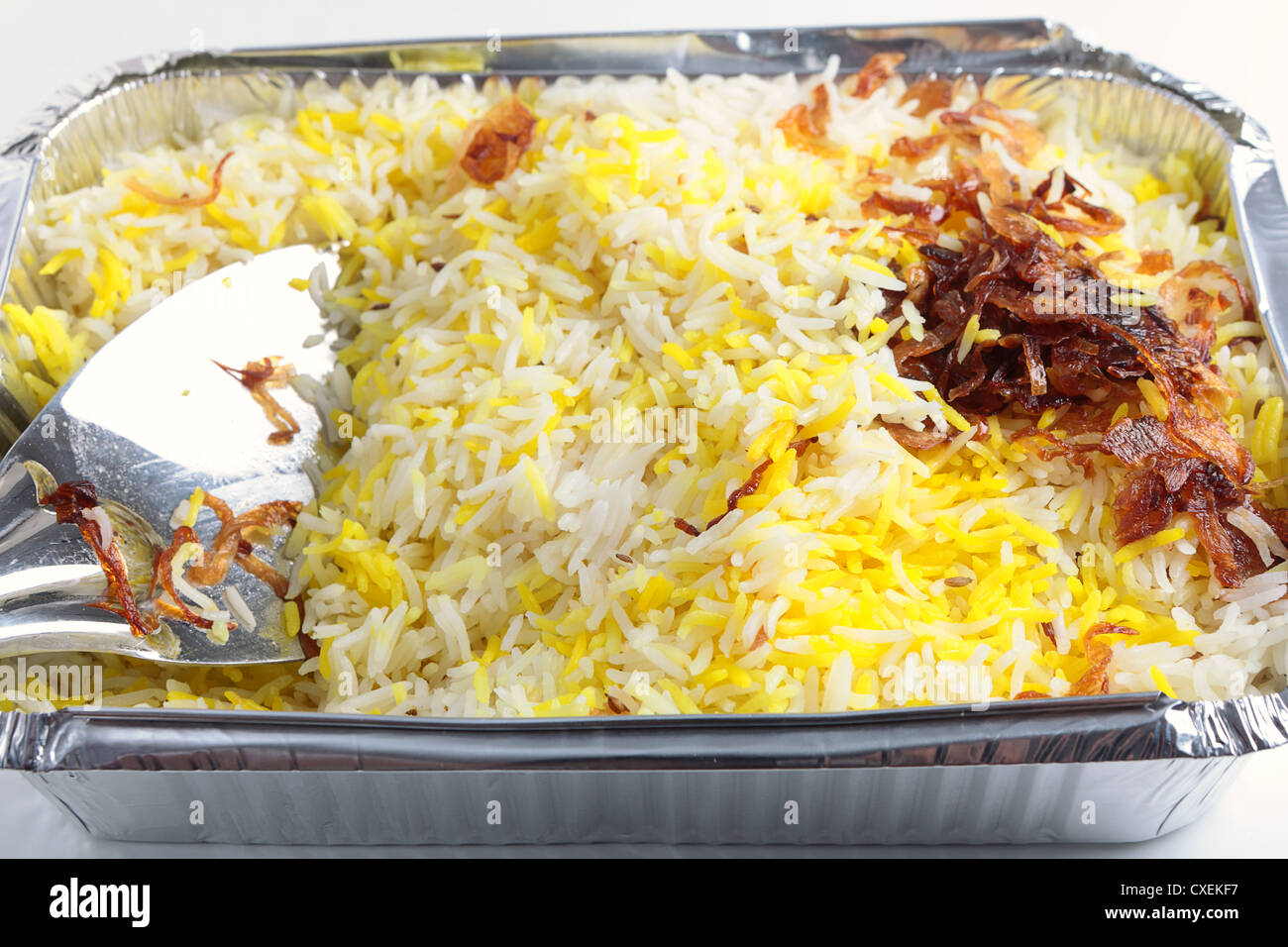 An indian restaurant's Pilau rice with onion garnish takeaway in an aluminium tray with a rice