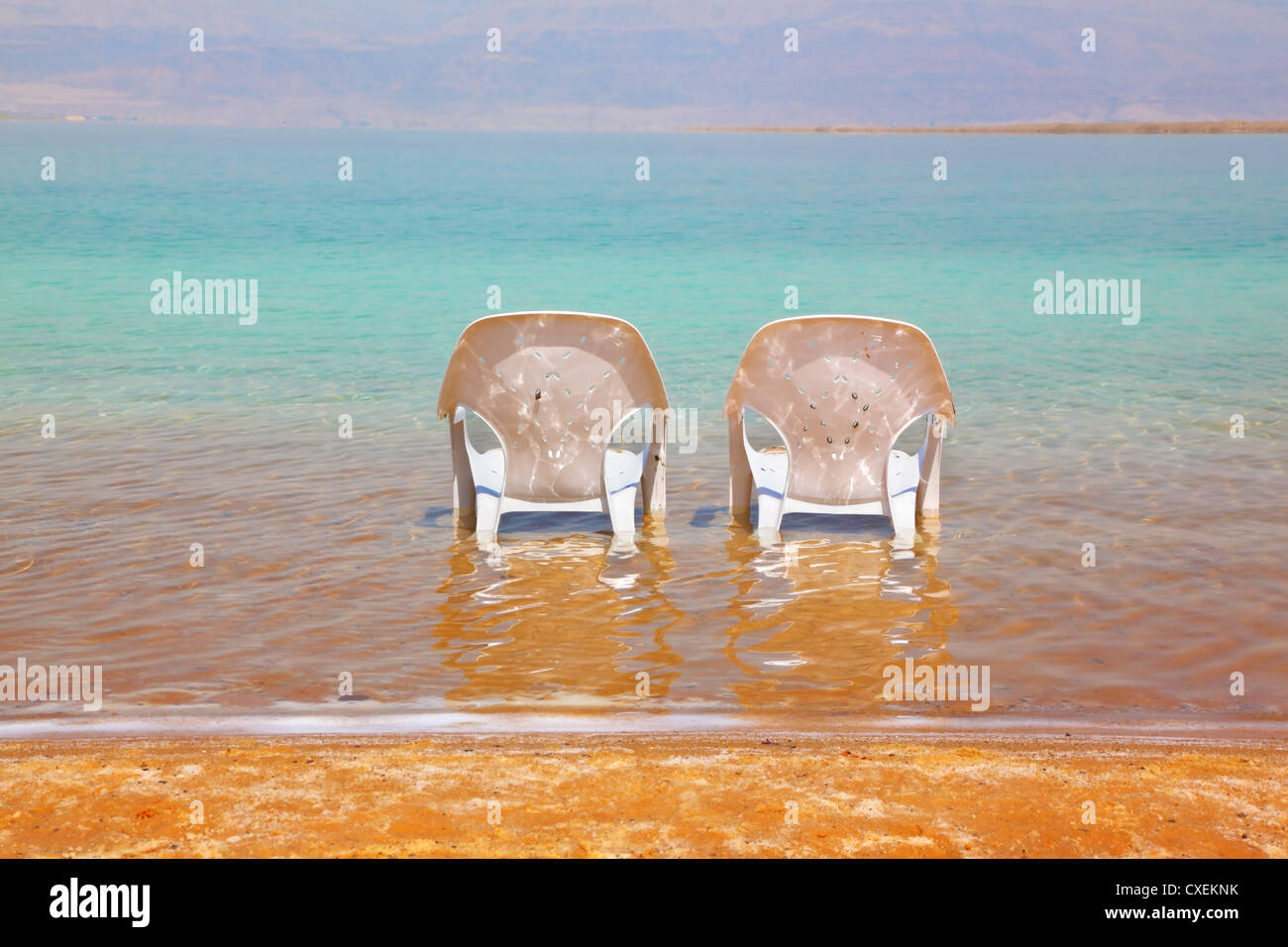 Two white beach chairs stood side by side Stock Photo