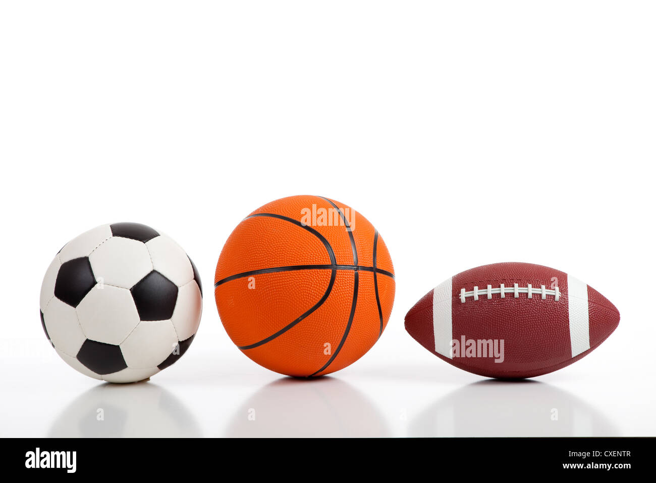 Assorted sports balls on a white background including a soccer ball, a basketball and an American football Stock Photo
