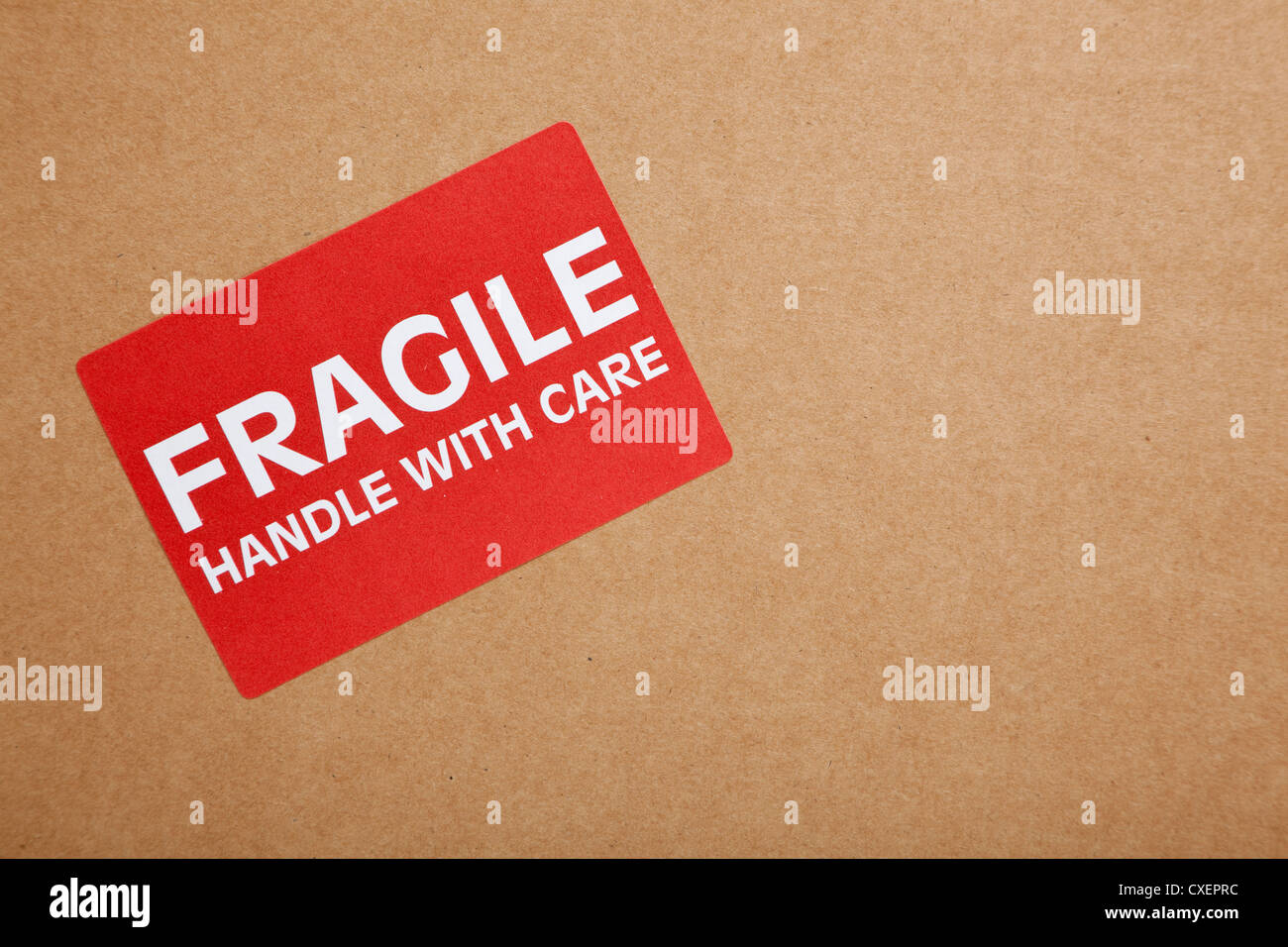 Red 'Handle with care' sticker on a plain brown wrapper Stock Photo