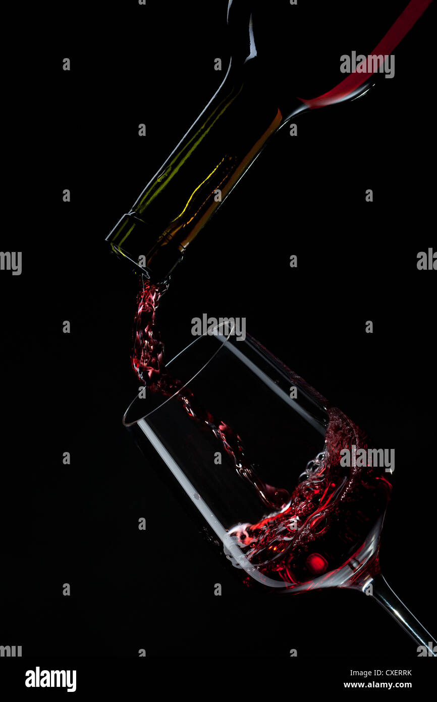 red wine pouring into wine glass isolated on black Stock Photo