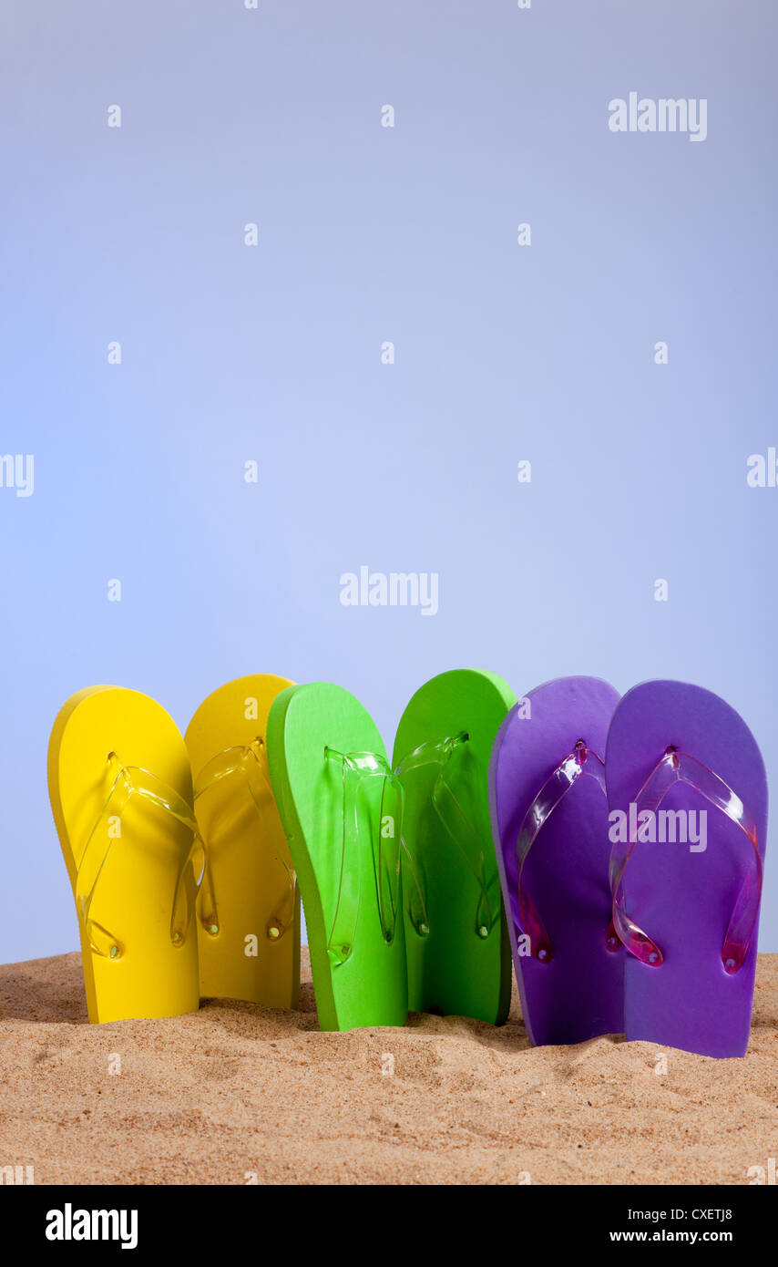 Assorted colored flipflops on a sandy beach with a sky clue background Stock Photo Alamy