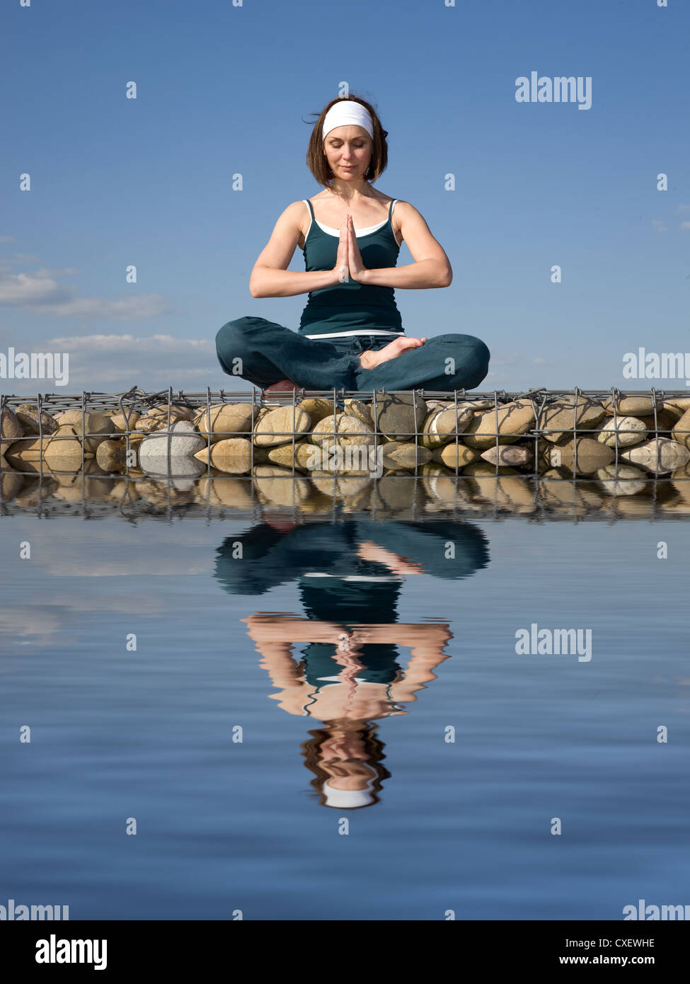 A woman doing yoga above a water Stock Photo