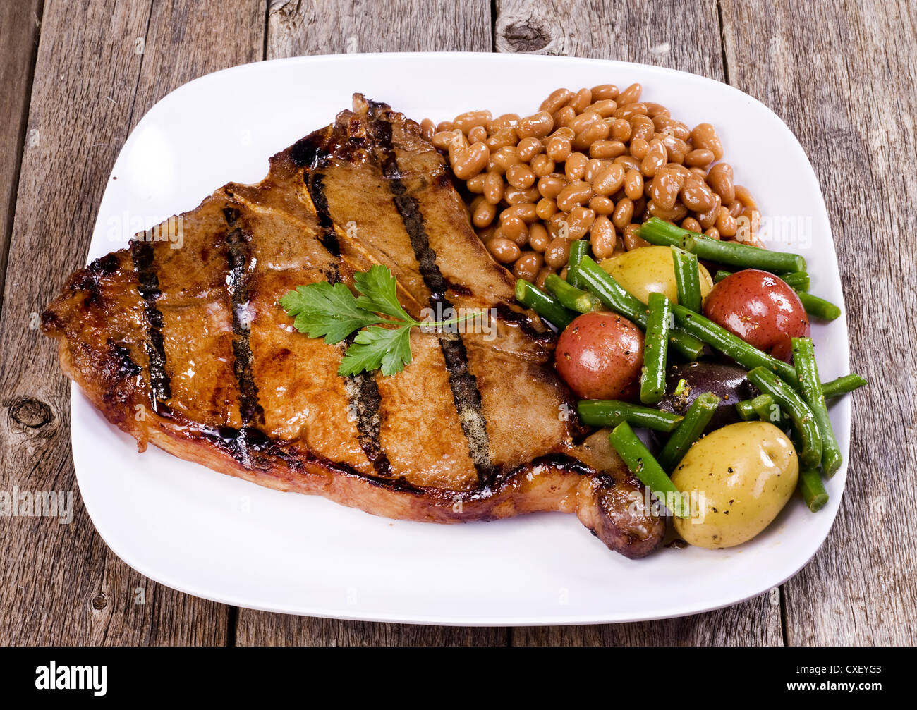 T-Bone Steak with pork and beans and vegetables. Stock Photo