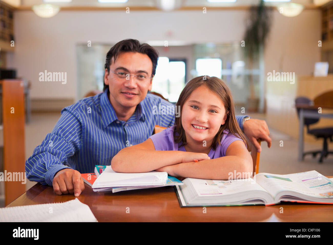 Teacher talking to student in library Stock Photo - Alamy
