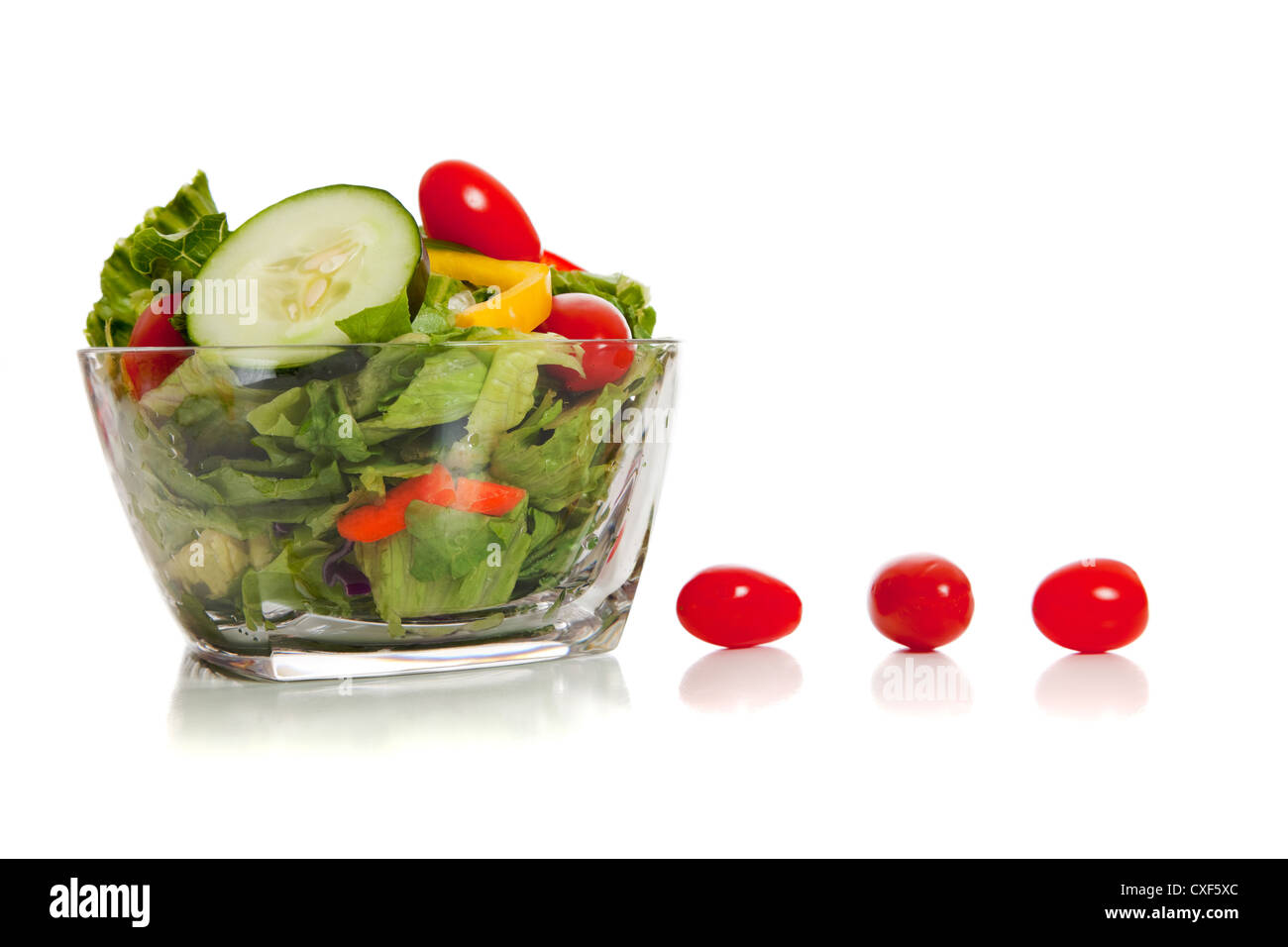 Glass bowl with tossed salad and row of cherry tomatioes Stock Photo